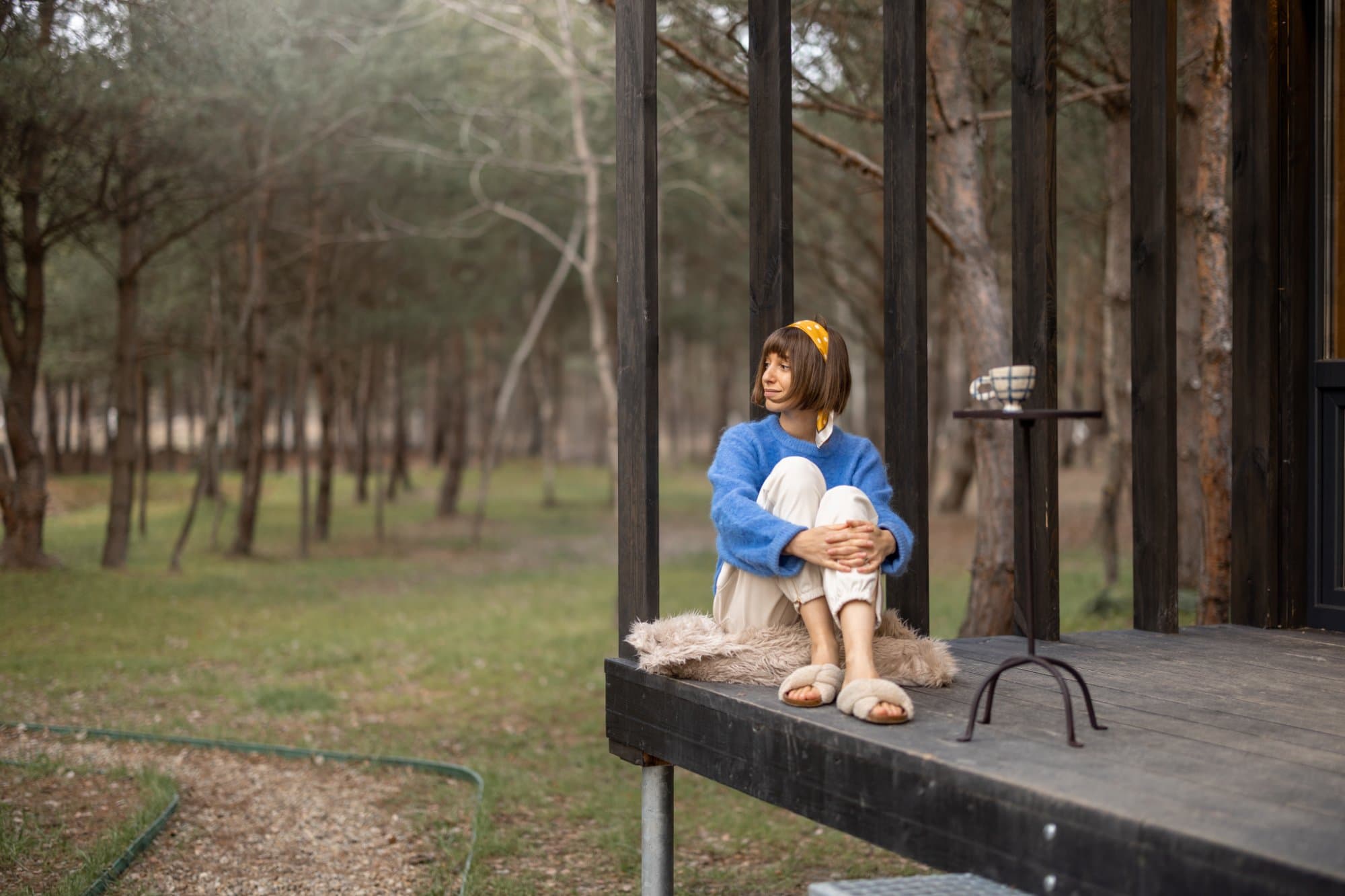 Woman resting near a wooden cottage in nature